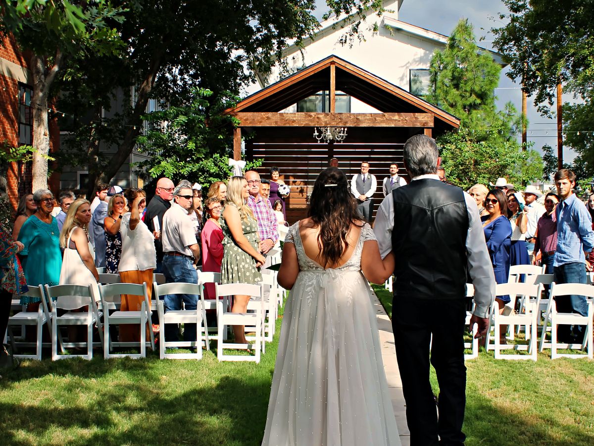 A bride walking down the aisle with her father, guests standing on both sides